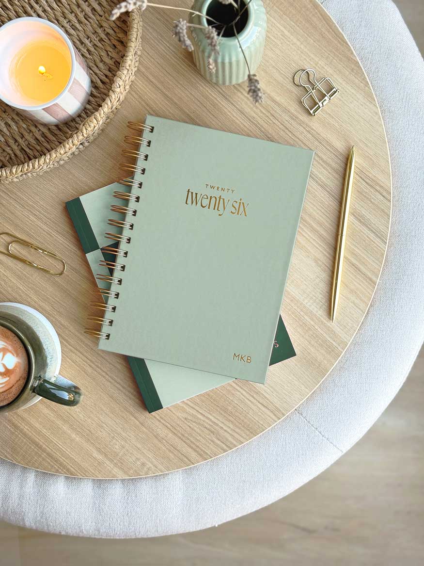sage green hardback diary with gold foiled embossed personalised initials and "2026" on the cover. the planner is A5 in size and features spiral binding to lay flat.
