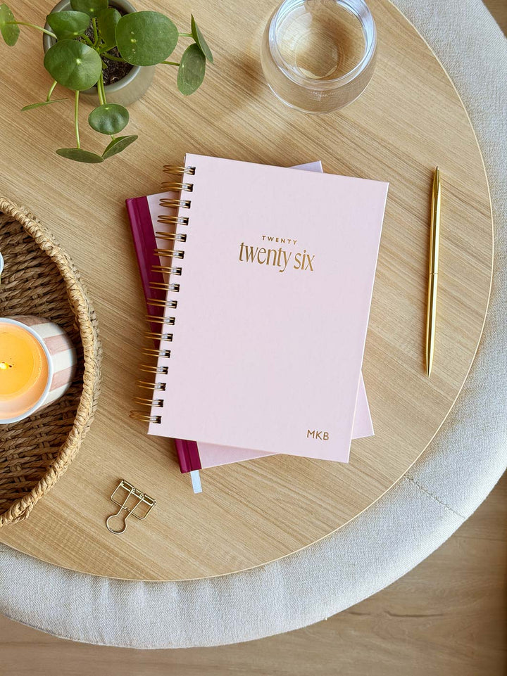 2026 spiral diary with pale pink cover and gold foiled personalisation on an office desk