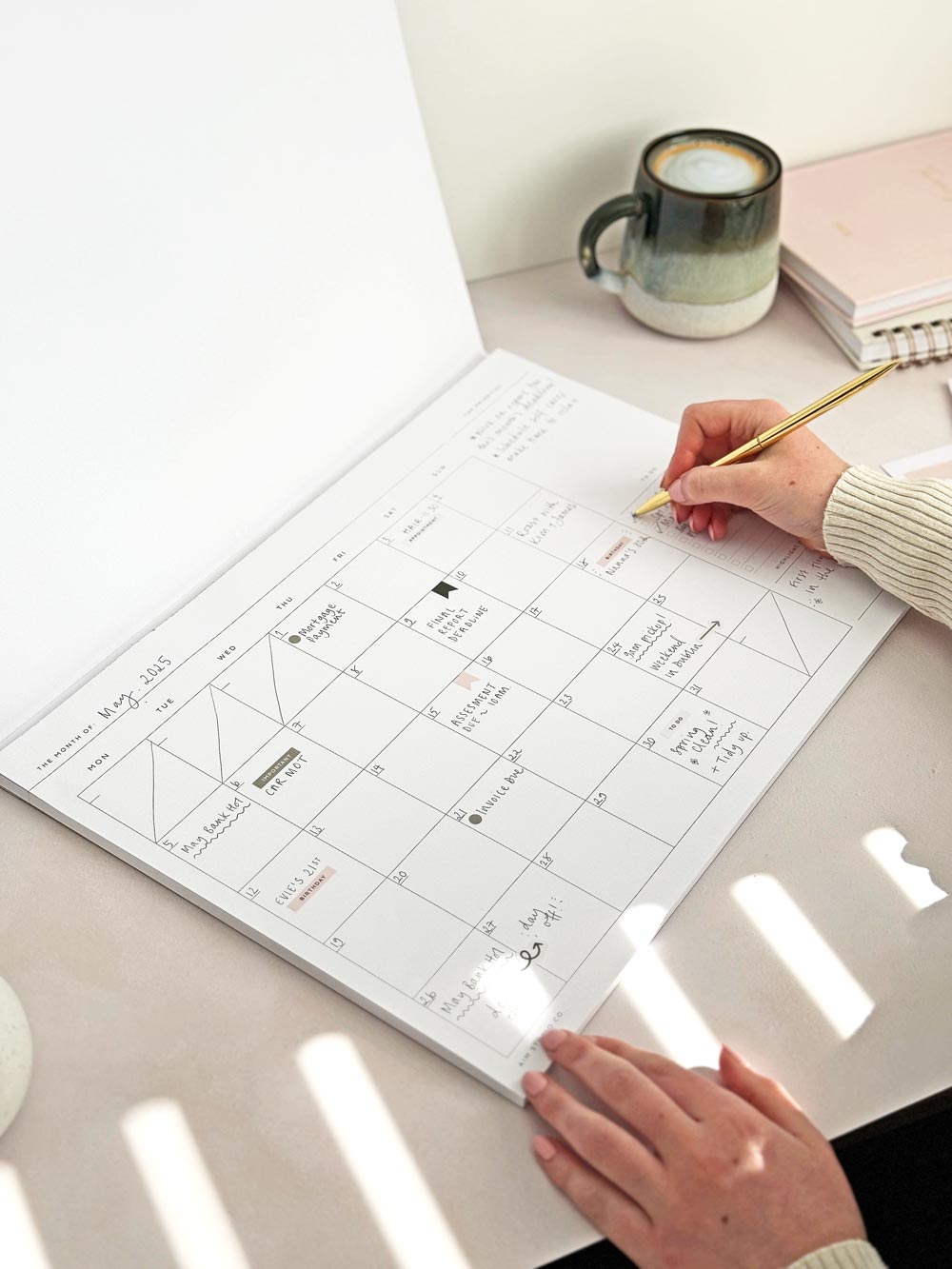 woman at office desk writing content plans on large undated monthly planner notepad