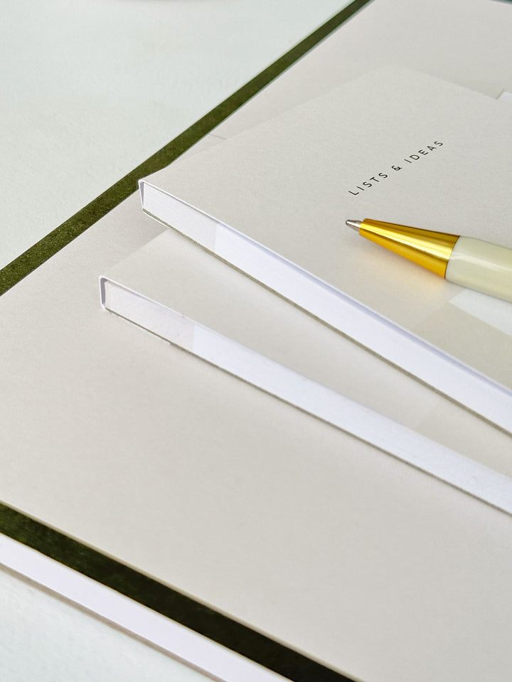to do list notepad with thick card cover stacked with various notepads and stationery accessories on a desk