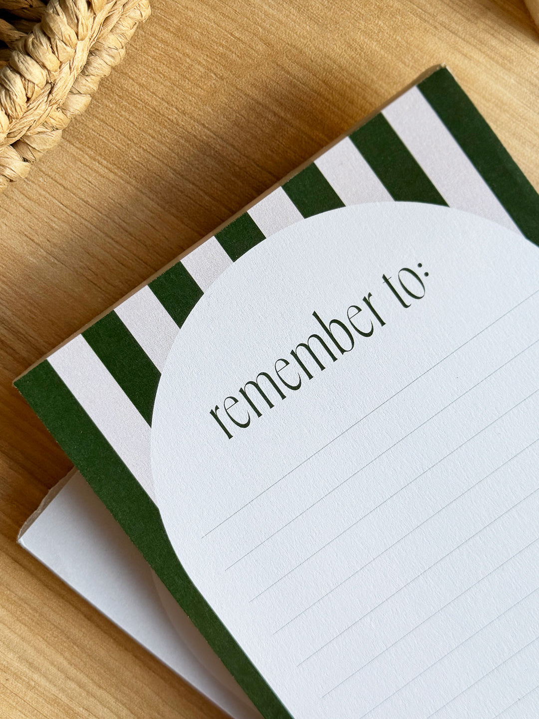 A6 notepad with "remember to" in green typography and aesthetic stripe design on office desk