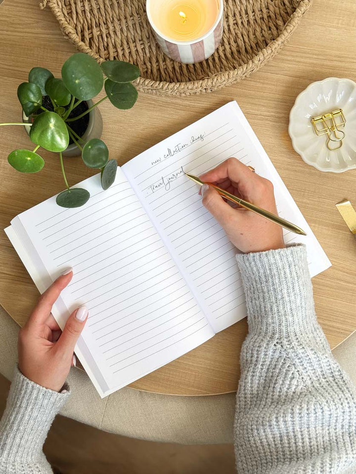women writing in lined A5 notebook on aesthetic desk setup with stationery and accessories