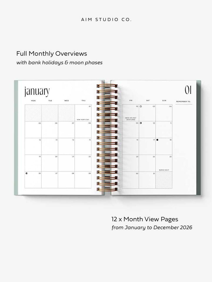 Open A5 hardback spiral-bound planner showing monthly calendar pages with text about features and layout.