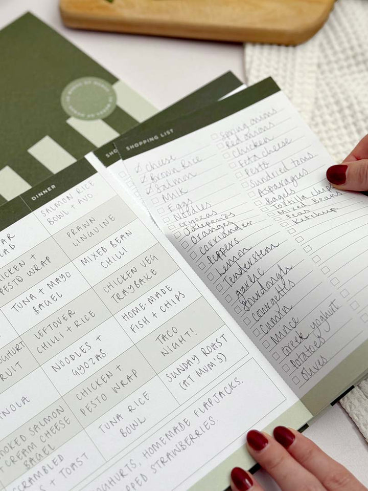 weekly meal planner with healthy meal prep ideas and woman removing perforated grocery list section of the notepad page.