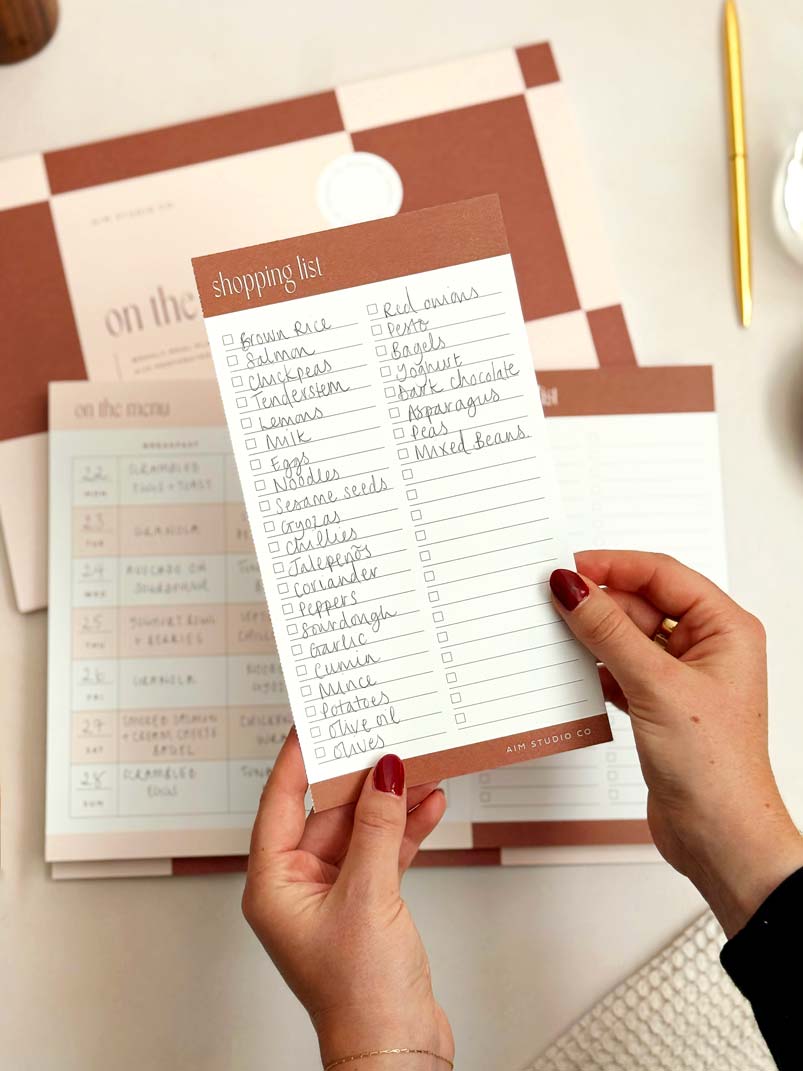 Person holding a shopping list with a checkered background