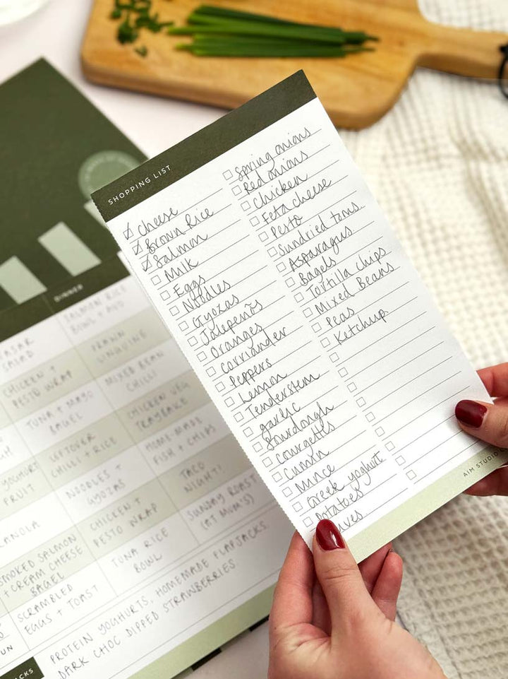 holding a shopping list which as been perforated from weekly menu planner