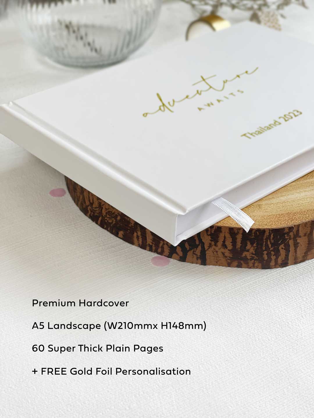 close up of a hardcover white memory book with plain pages and white ribbon bookmark with specifications listed next to it