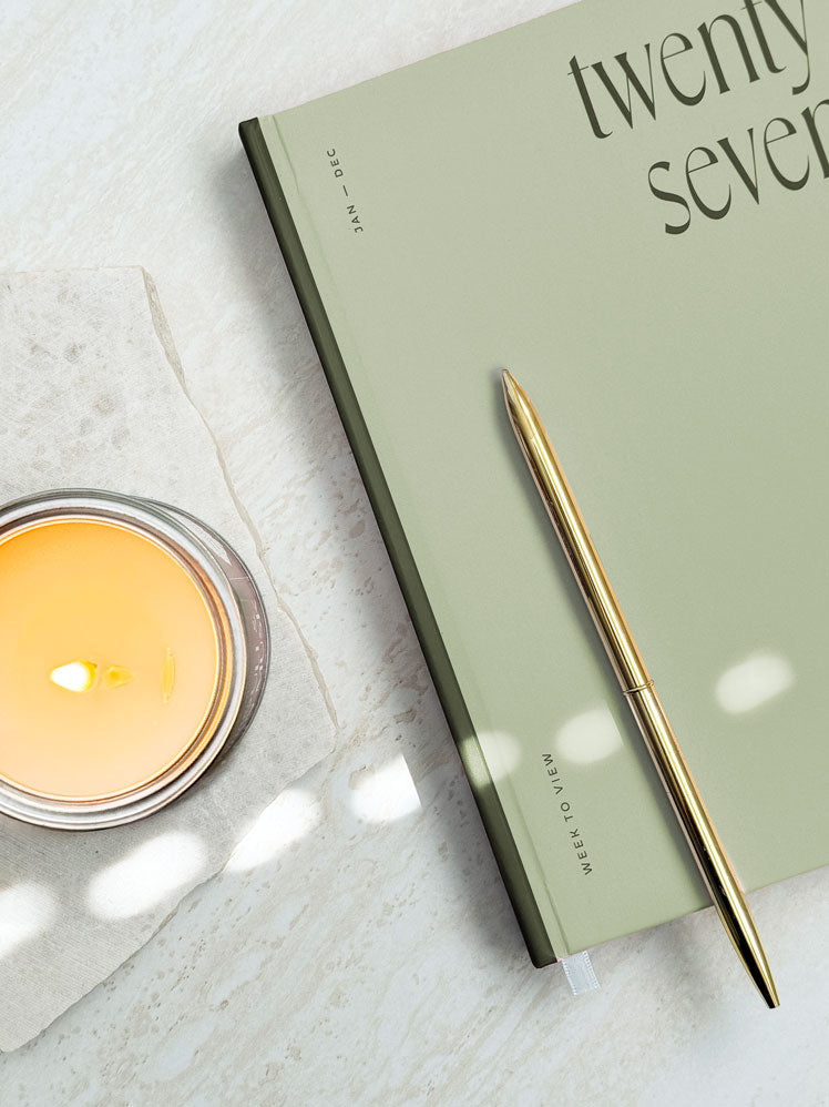 Close up of A5 sized hardcover planner with sage green cover and deep green spine with large 2027 text on the cover.