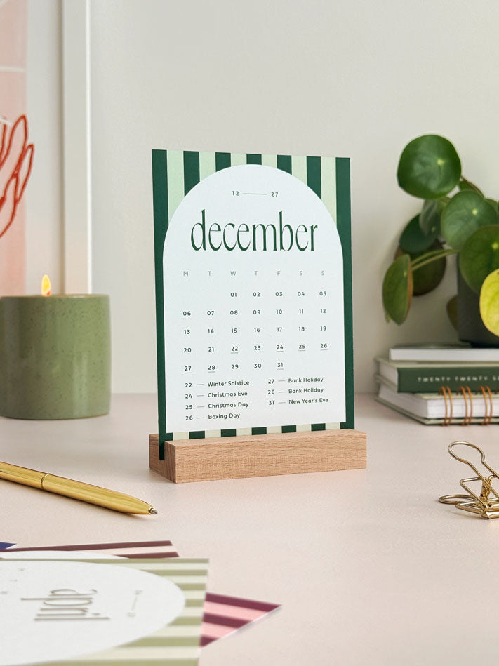 A6 sized calendar card showing december 2027 with deep green and sage green stripe with white arch containing month to view calendar grid and bank holidays.
