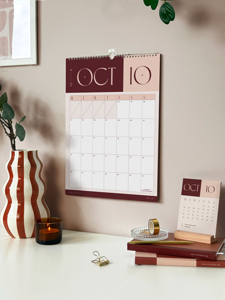 Hanging spiral-bound wall calendar showing october 2027 with month to view planner and bold colour block design in brown and neutral tones.
