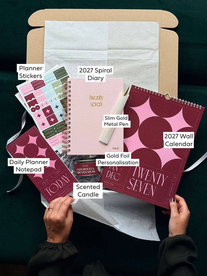 2027 spiral diary gift set with matching pink and burgundy stationery, including a wall calendar, slim notepad, planner stickers and gold pen.