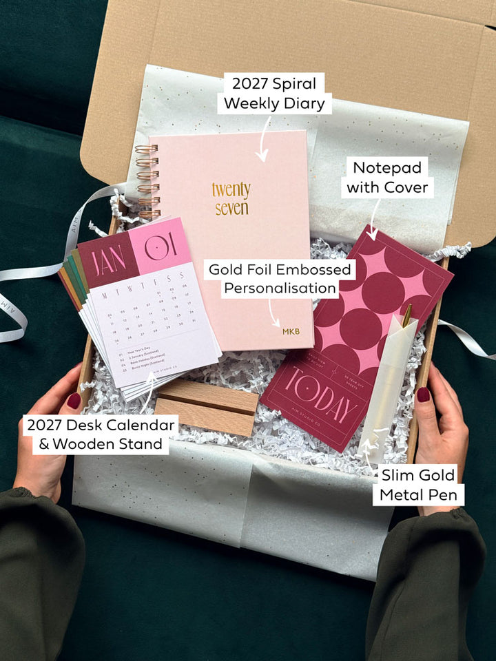 text with arrows highlighting the contents of a desk accessories and stationery gift bundle, with a personalised spiral diary, notepad, pen and desk calendar.
