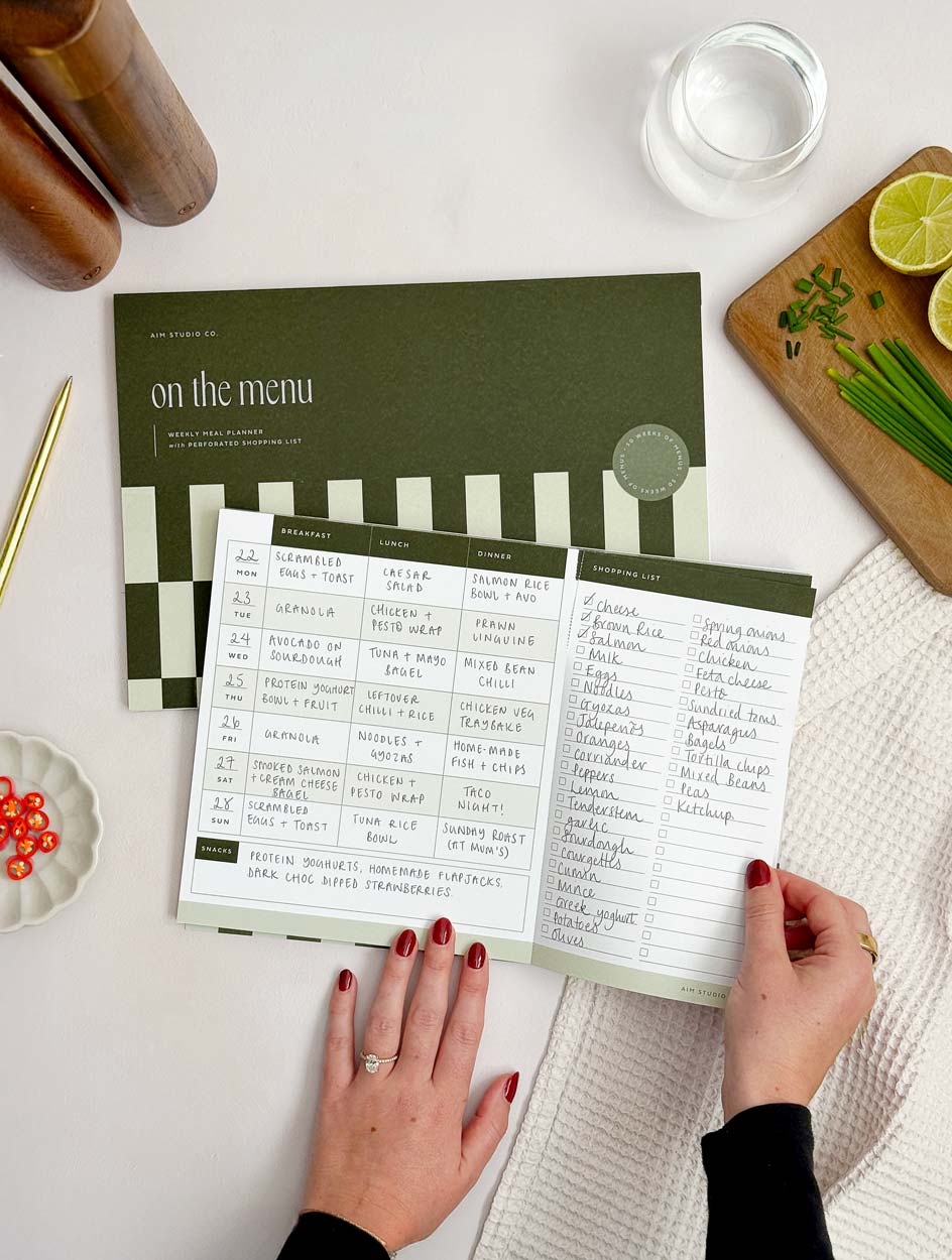 person using weekly meal planner notepad to tear off perforated shopping list section