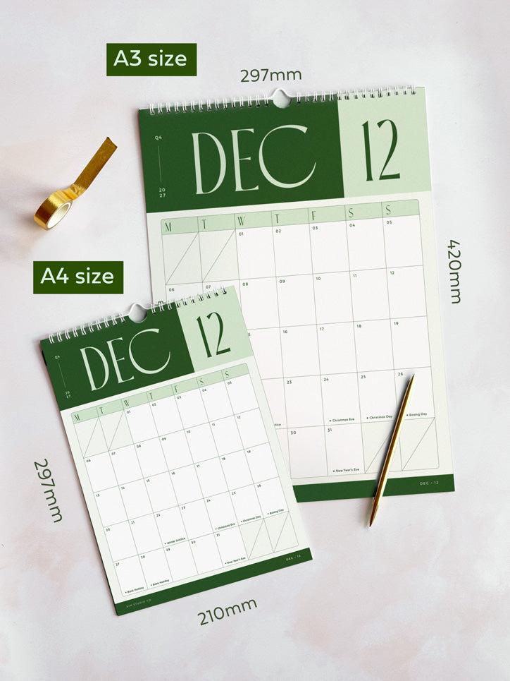 Two spiral-bound 2027 wall calendar pages showing December 2027, one A3 size and one A4 size, laid on a light background with size labels and a gold pen.
