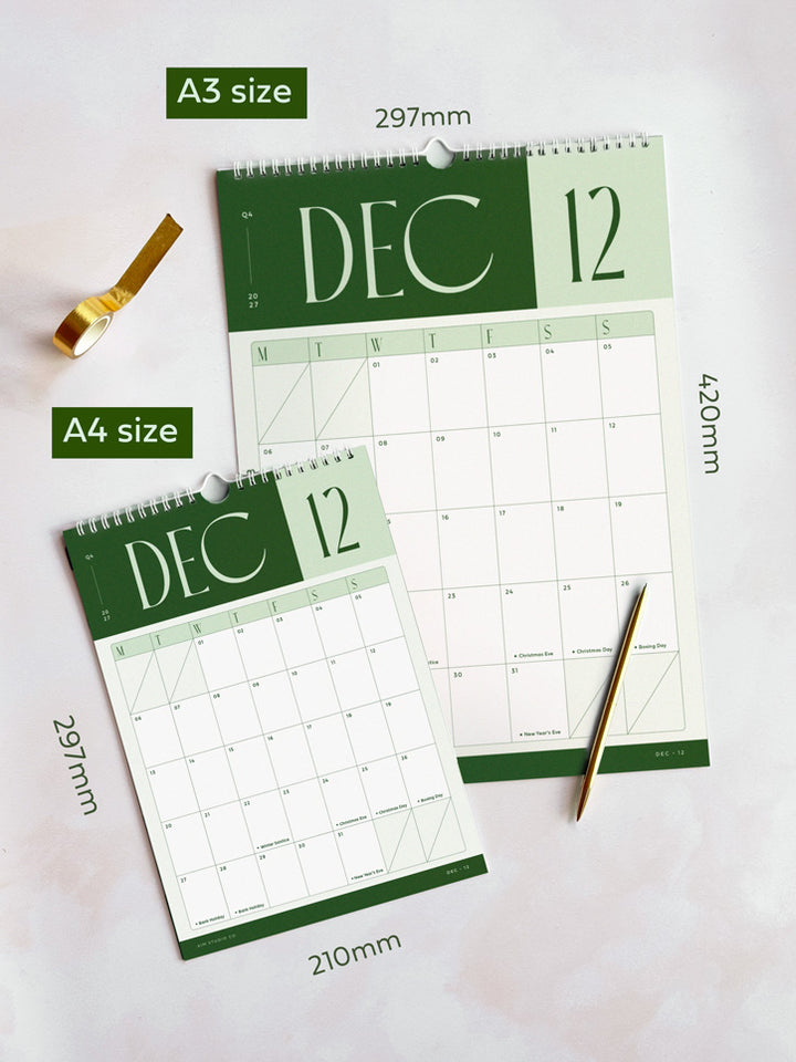 Two spiral-bound 2027 wall calendar pages showing December 2027, one A3 size and one A4 size, laid on a light background with size labels and a gold pen.