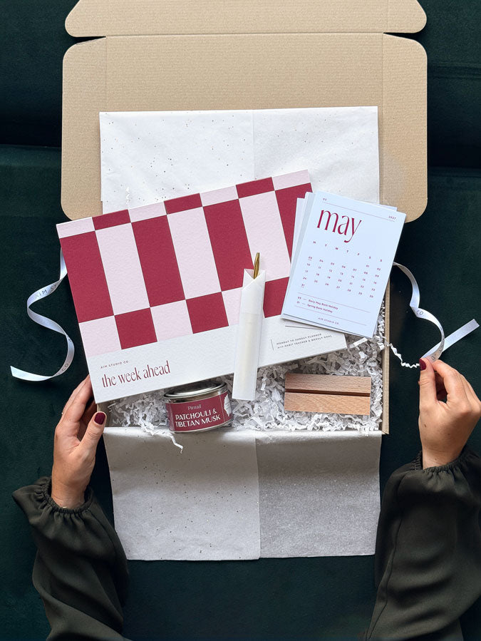 The Weekly Reset Set: an A4 weekly planner and 2027 desk calendar stationery bundle in a gift box, with a gold pen and scented mini candle.