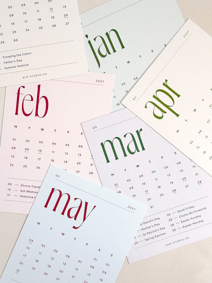 scattered a6 monthly calendar cards in minimal design showing soft neutral and muted background colours with bold contrasting typography.