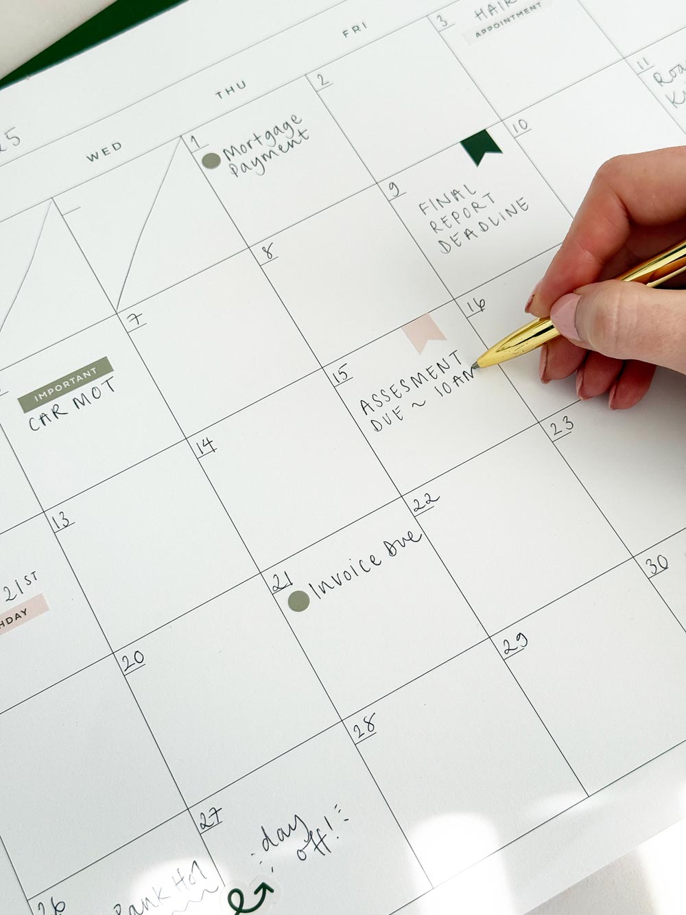 woman writing on monthly wall calendar with cute planner stickers