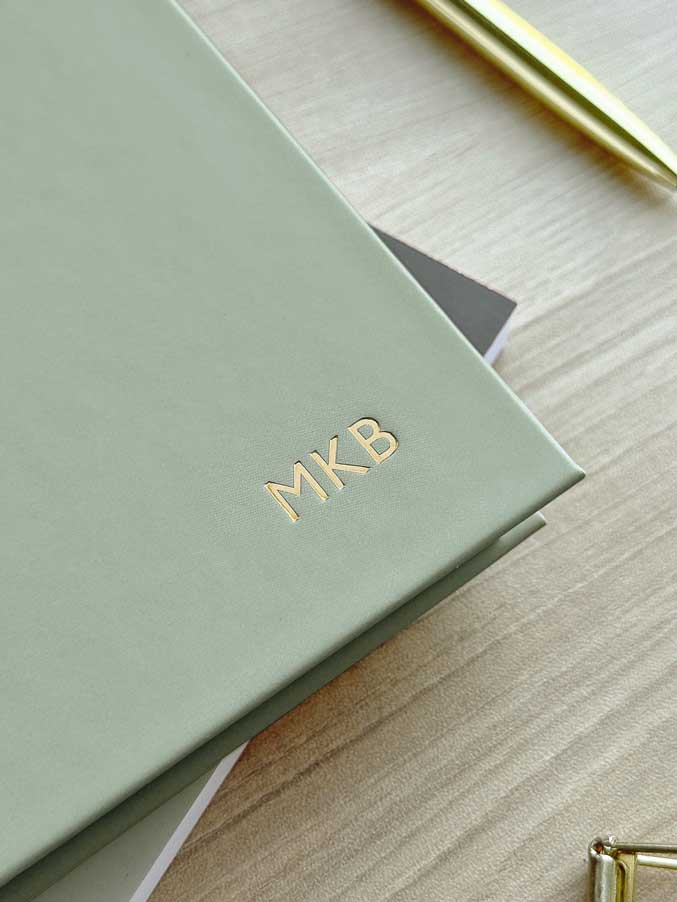 close up of personalised monogram stamped in gold foil on the cover of a hardback sage green 2026 diary