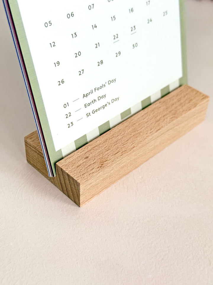 close up of wooden desk calendar holder with green A6 striped card.