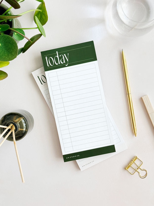 time blocking Notepad with 'today' on top, surrounded by office supplies on a light surface.