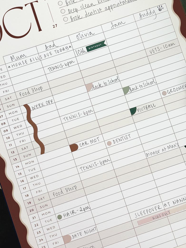 close up of october 2027 monthly calendar page inside AIM Studio Co's large A3 family wall planner. The page is filled in with plans for each family member and decorated with matching planner stickers.
