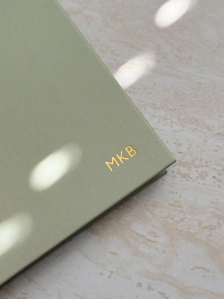close up of gold foiled personalised initials embossed into the cover of sage green weekly planner by AIM Studio Co.