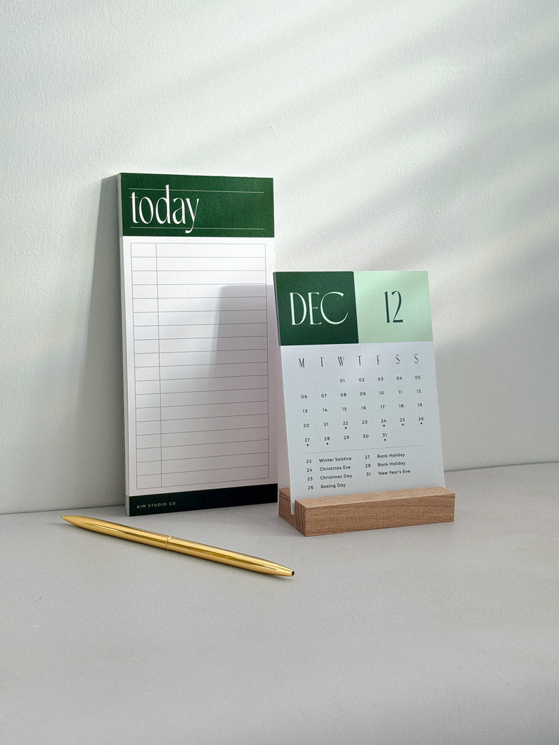 The Daily Focus Set: a green themed Secret Santa gift bundle with a forest green time blocking planner and 2027 desk calendar with wooden stand.