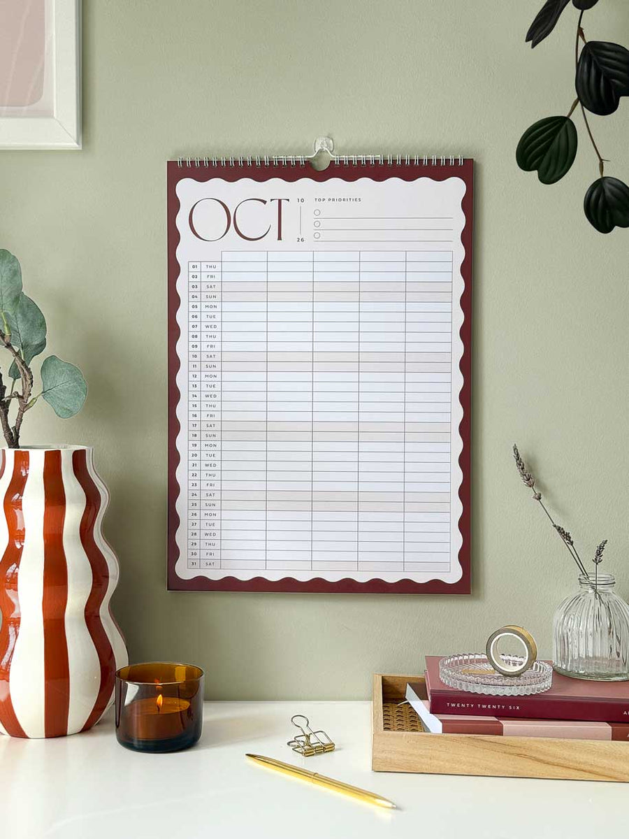 family Wall calendar for October 2026 on a light green wall with aesthetic decorative items below.