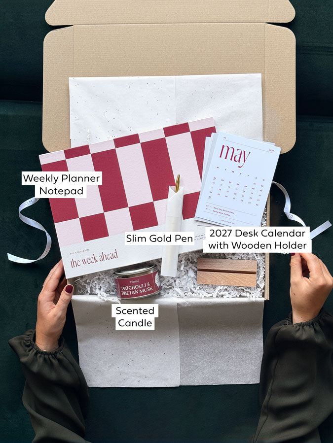 Labelled items inside the Weekly Reset Set, a stationery and desk accessory gift box for her: A4 weekly planner, desk calendar with wooden stand, gold pen and candle.