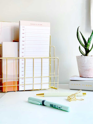 time blocking planner pad on an office desk with stationery and desk plant