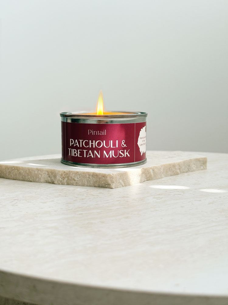 Patchouli and Tibetan musk scented candle in a mini paint pot tin with a burgundy label, included in AIM Studio Co gift sets.