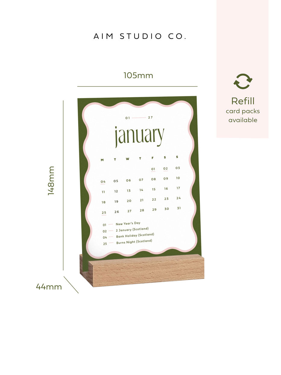 a6 monthly calendar card showing January 2027 held in a wooden block stand with size dimensions reading 105 x 148mm.