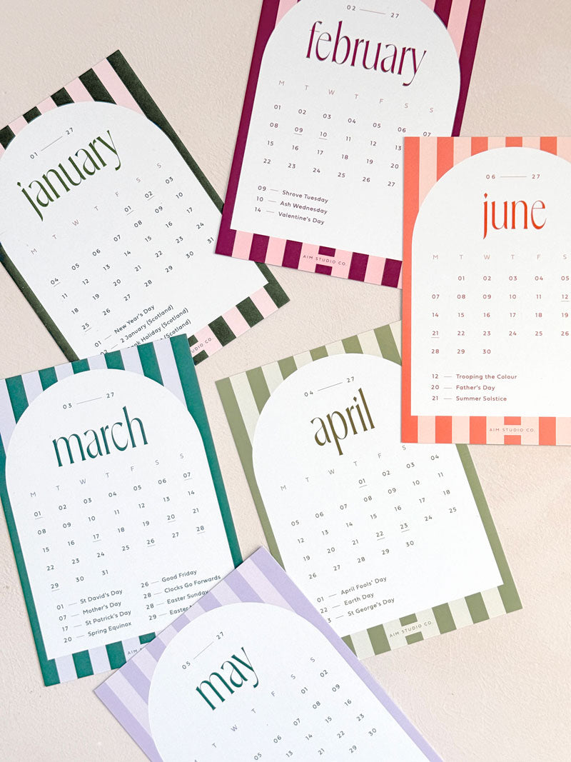 a set of printed monthly calendar cards for 2027 with stripe design for each month. Shows various colourful calendar cards al with UK bank holidays marked.