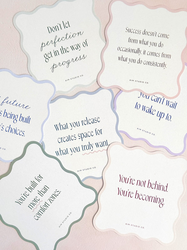 decorative daily quote cards scattered on a surface showing wavy-cut scalloped edges in various pastel shades. Each card displays a positive affirmation in a modern serif font, themed around personal growth, success mindset and confidence.