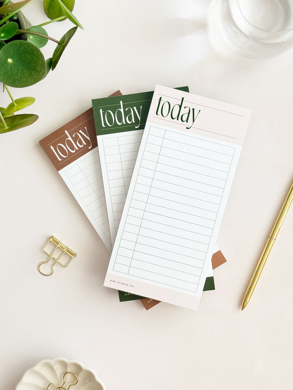 Three slim daily planner notepads with 'today' text on an aesthetic office desk with a plant and pen.
