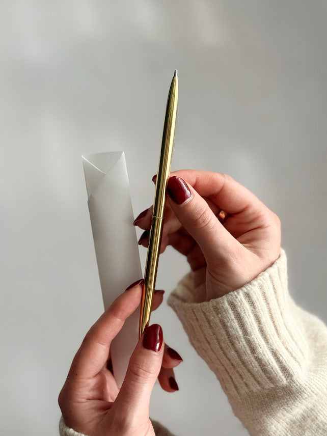 A close up of a slim gold pen and it&
