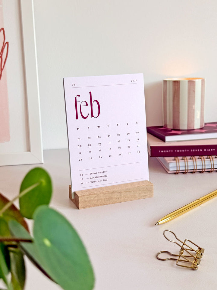 a minimalist monthly desk calendar showing soft pink card of february 2027 with large serif typography and minimal calendar date grid with UK bank holidays marked.