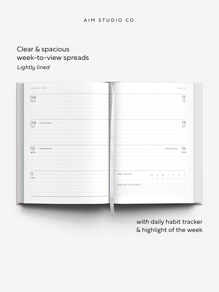 Week to view planner spread across two a5 pages with lined daily sections, UK bank holidays, and a daily habit tracker. A white ribbon bookmark lies across the page.