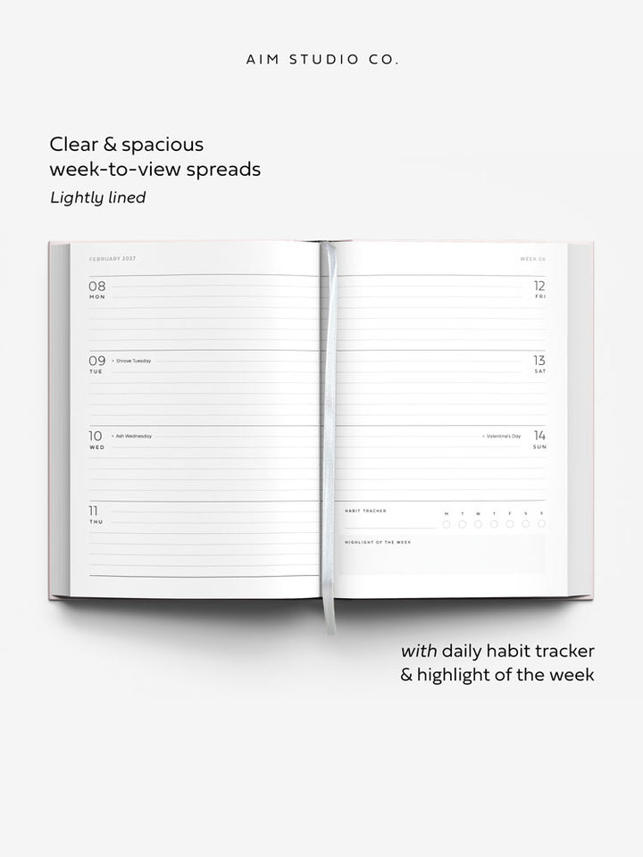 Week to view planner spread across two a5 pages with lined daily sections, UK bank holidays, and a daily habit tracker. A white ribbon bookmark lies across the page.