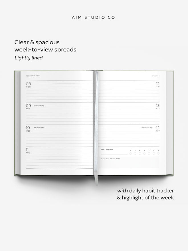 An open weekly planner spread from Aim Studio Co. with text describing clear spacious week-to-view spreads and a daily habit tracker.
