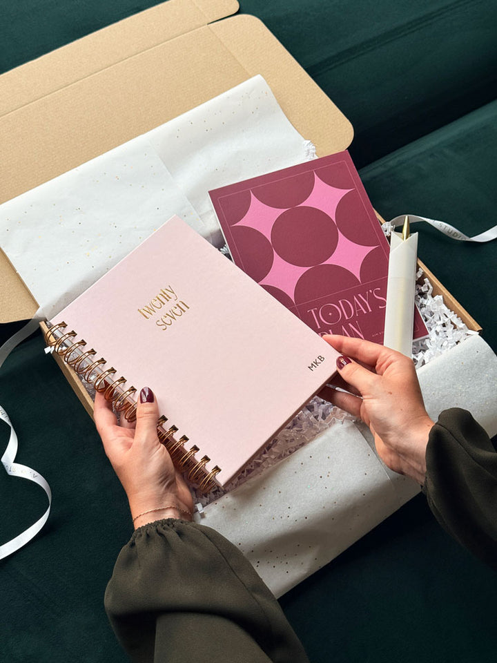 a person holding a spiral 2027 week to view planner with gold foiled &
