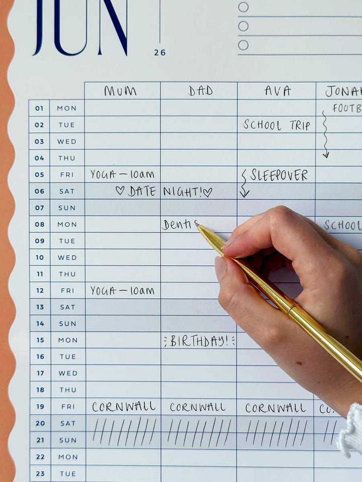 hand writing in family plans on hanging wall calendar page with 5 columns and colourful wavy border design.