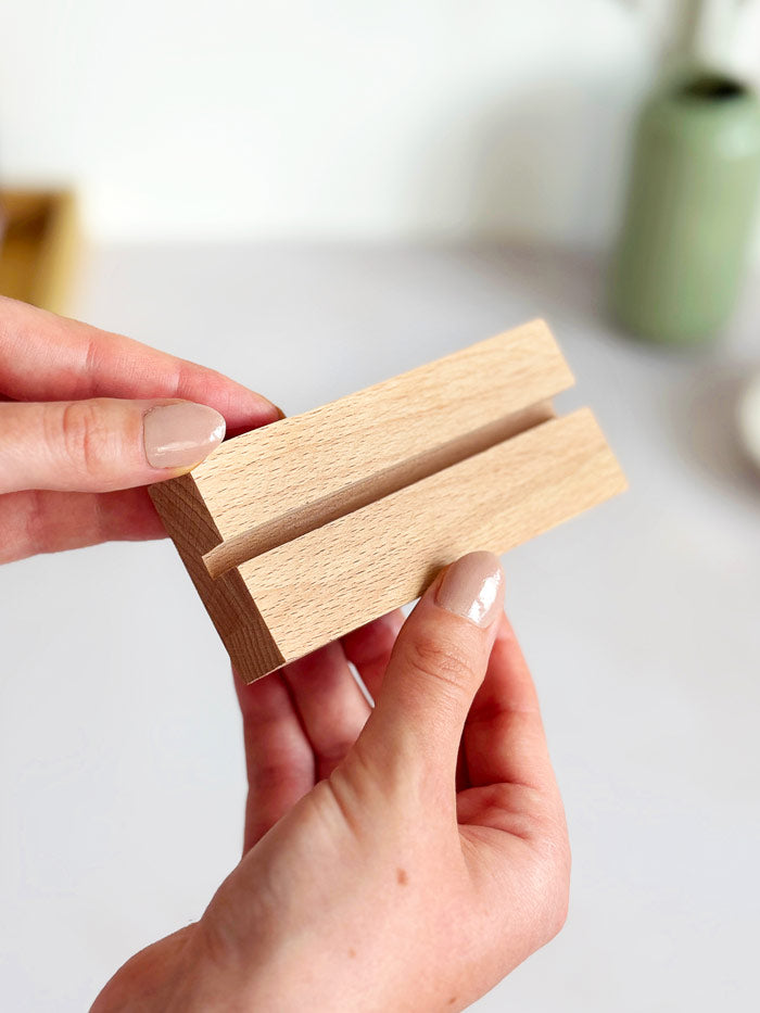 close up of a wooden holder with a slot to display positive affirmation quote cards on a desk. 