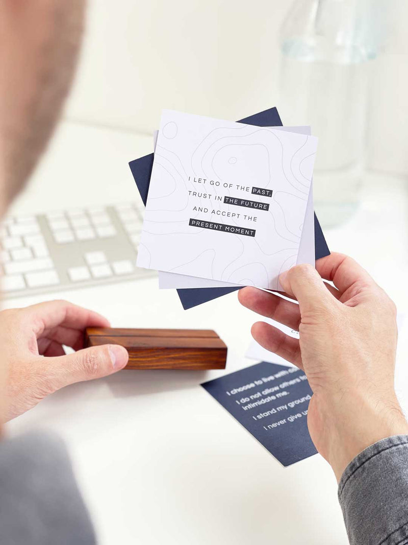 Man looking through mini prints with positive affirmation and inspirational phrases to display on his office desk