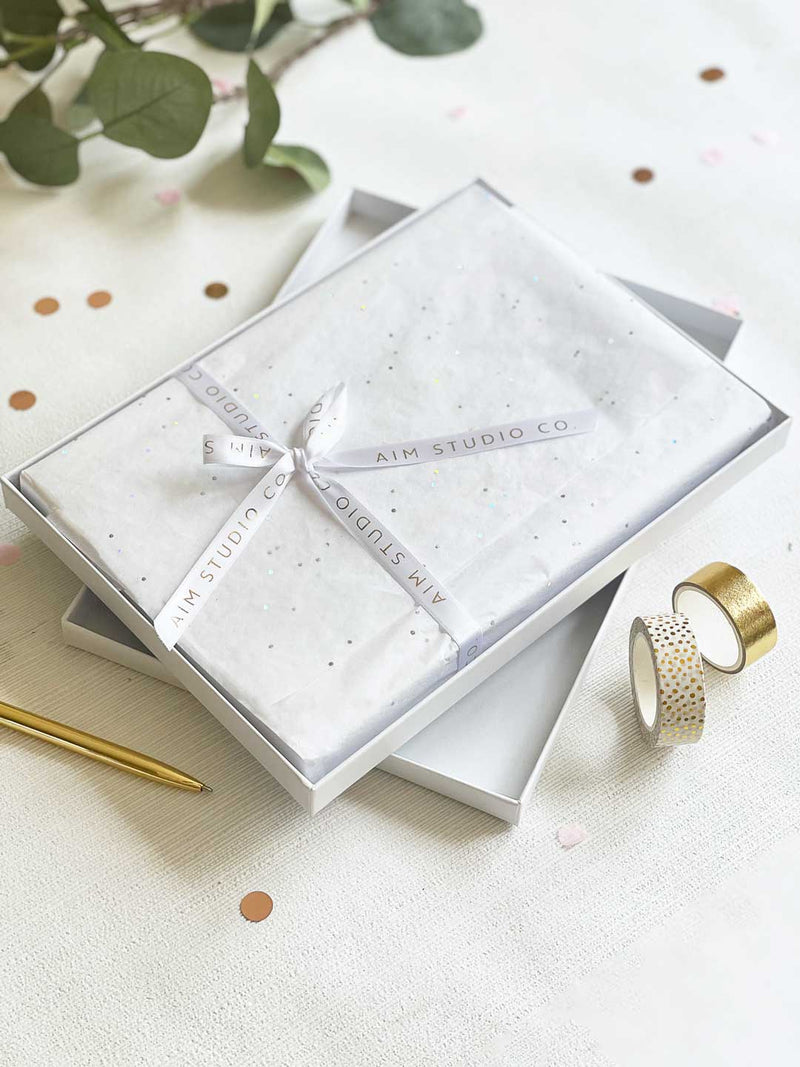 Gift wrapped memory book personalised with gold foil wrapped in white tissue paper with AIM Studio Co branded ribbon within a white gift box 