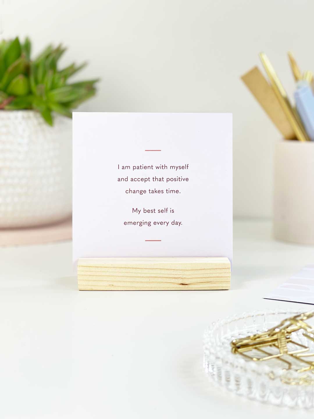 A positive card desk accessory for self confidence placed on a bright desk space surrounded by stationery