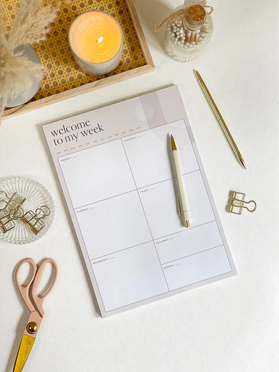 Large A4 desk planner notepad on a desk surrounded by aesthetic gold stationery and desk accessories