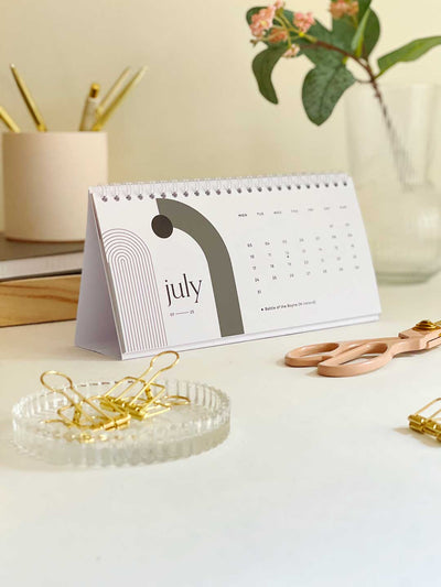Modern abstract desk calendar showing July 2023 surrounded by office accessories
