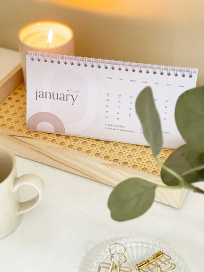Minimalist abstract desk calendar design standing in decorative tray showing a month view of January 2023